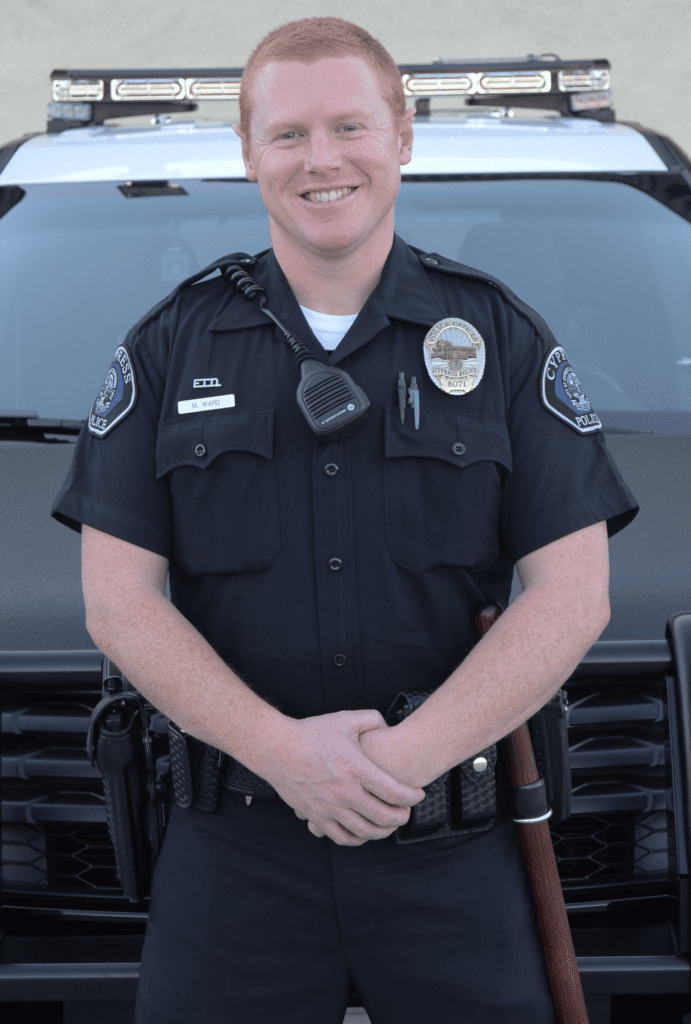 A police officer standing in front of a car.