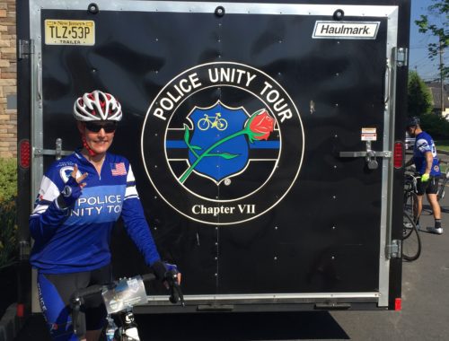 A man in blue shirt standing next to bicycle.