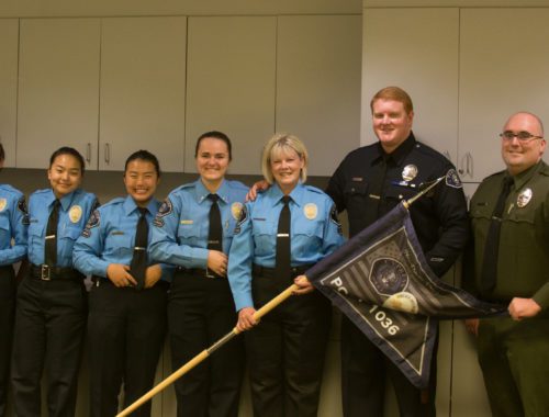 A group of people in police uniforms holding a flag.