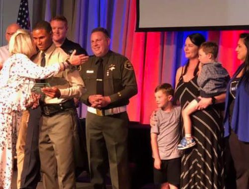 A group of people standing on stage with police officers.