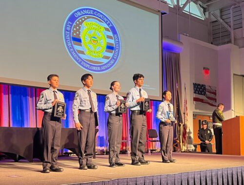 A group of young men standing on stage in front of an american flag.