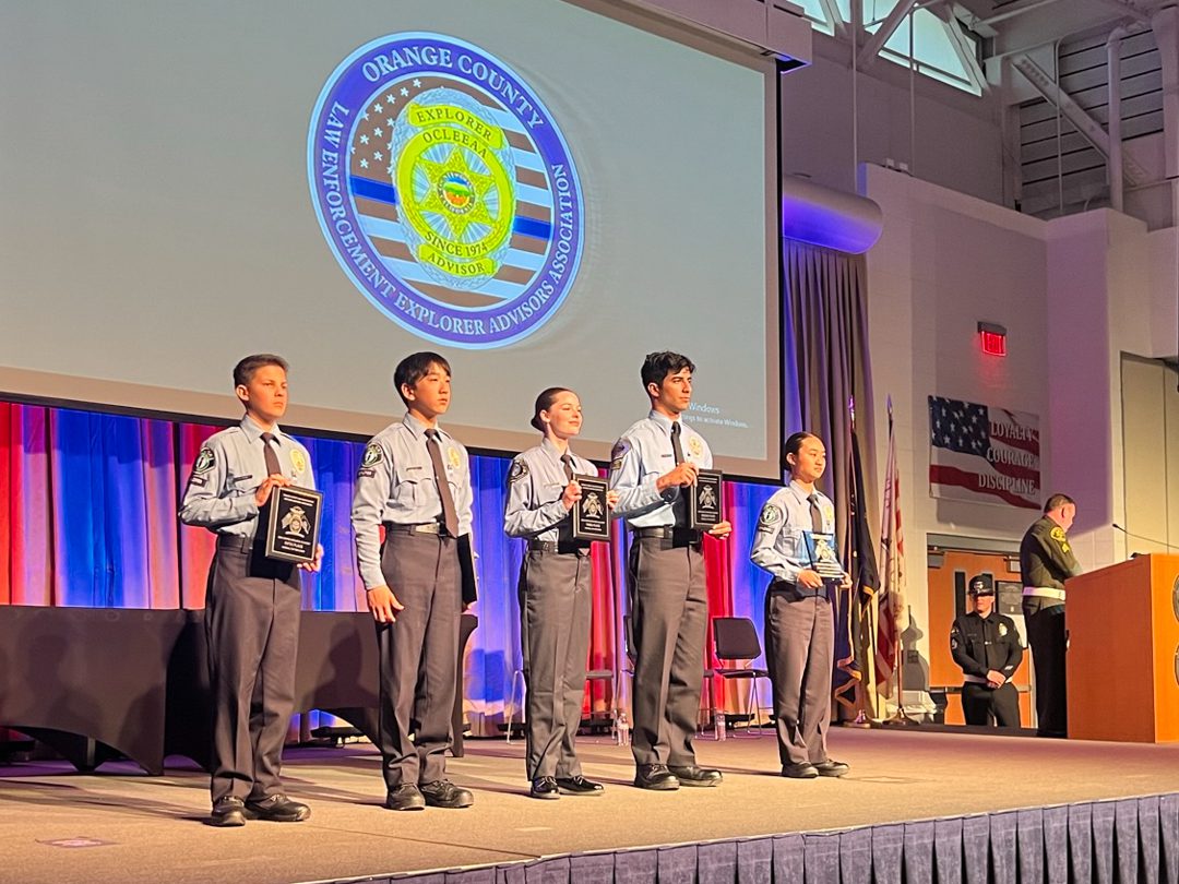 A group of young men standing on stage in front of an american flag.