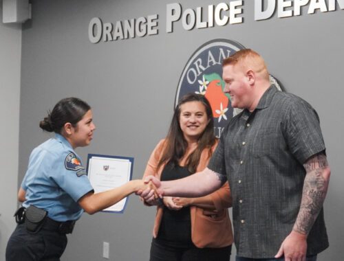 A police officer shaking hands with two people.