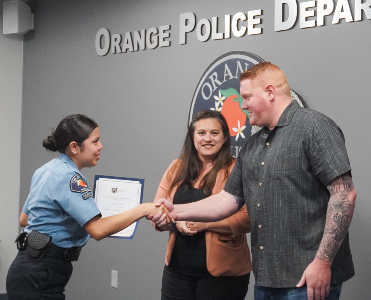 A police officer shaking hands with two people.